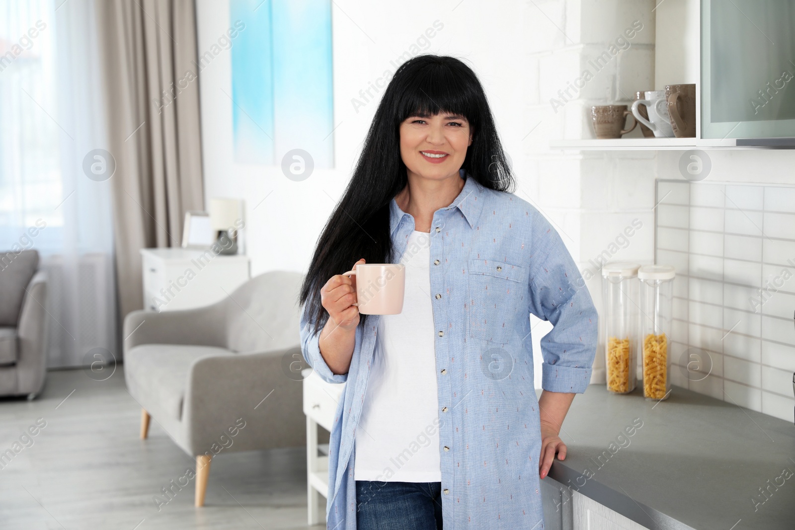 Photo of Beautiful mature woman with cup of drink at home