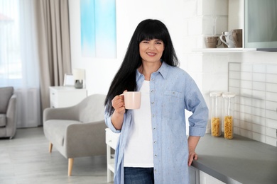 Photo of Beautiful mature woman with cup of drink at home