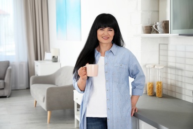 Beautiful mature woman with cup of drink at home