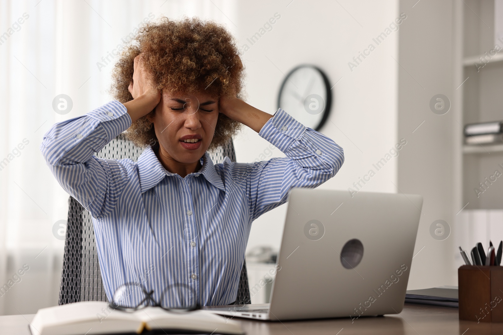 Photo of Woman suffering from headache at workplace in office