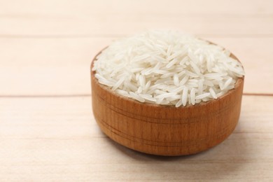 Photo of Raw basmati rice in bowl on white wooden table, closeup