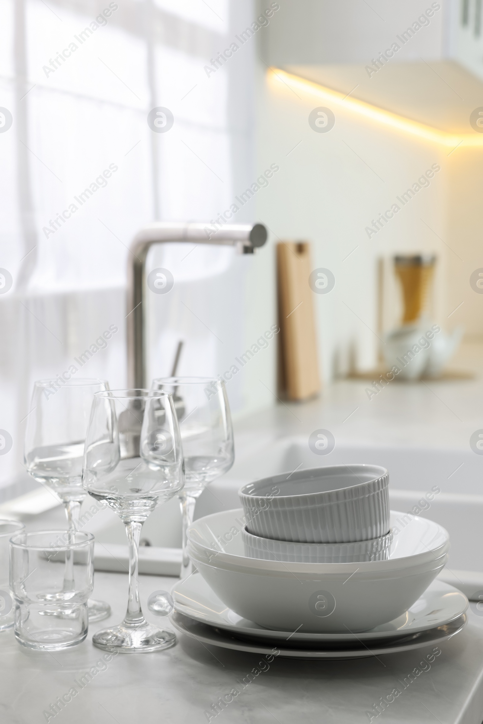 Photo of Different clean dishware and glasses on countertop near sink in kitchen, space for text