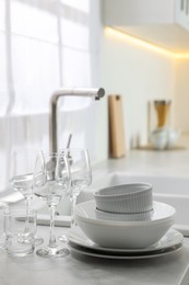 Photo of Different clean dishware and glasses on countertop near sink in kitchen, space for text