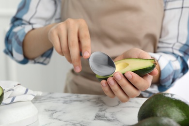 Photo of Woman with half of delicious ripe avocado and spoon at marble table, closeup