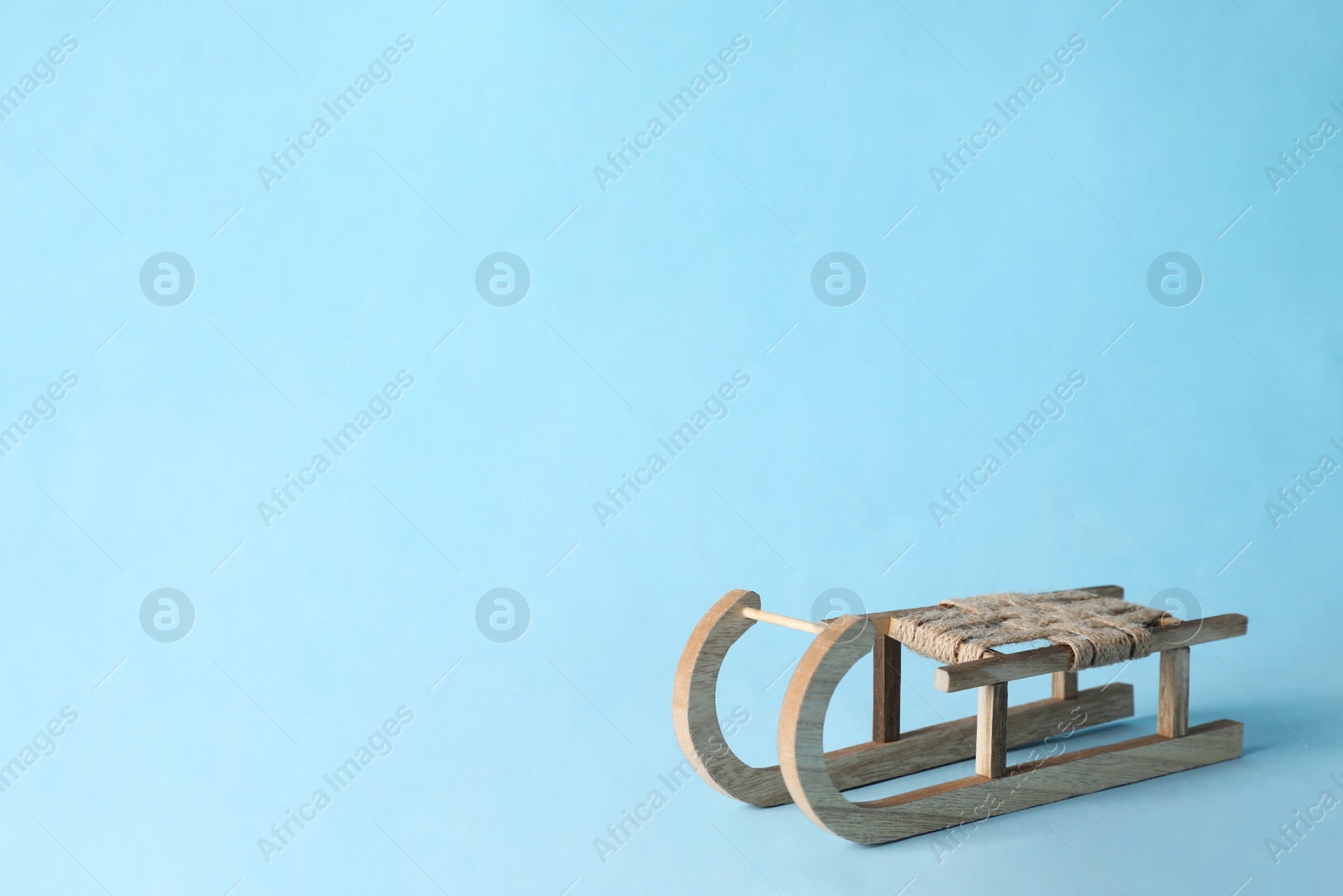 Photo of Beautiful decorative wooden sleigh on light blue  background, space for text