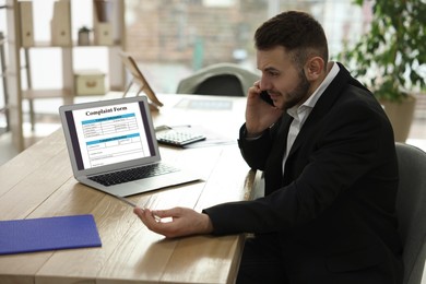 Man filling online complaint form via laptop in office