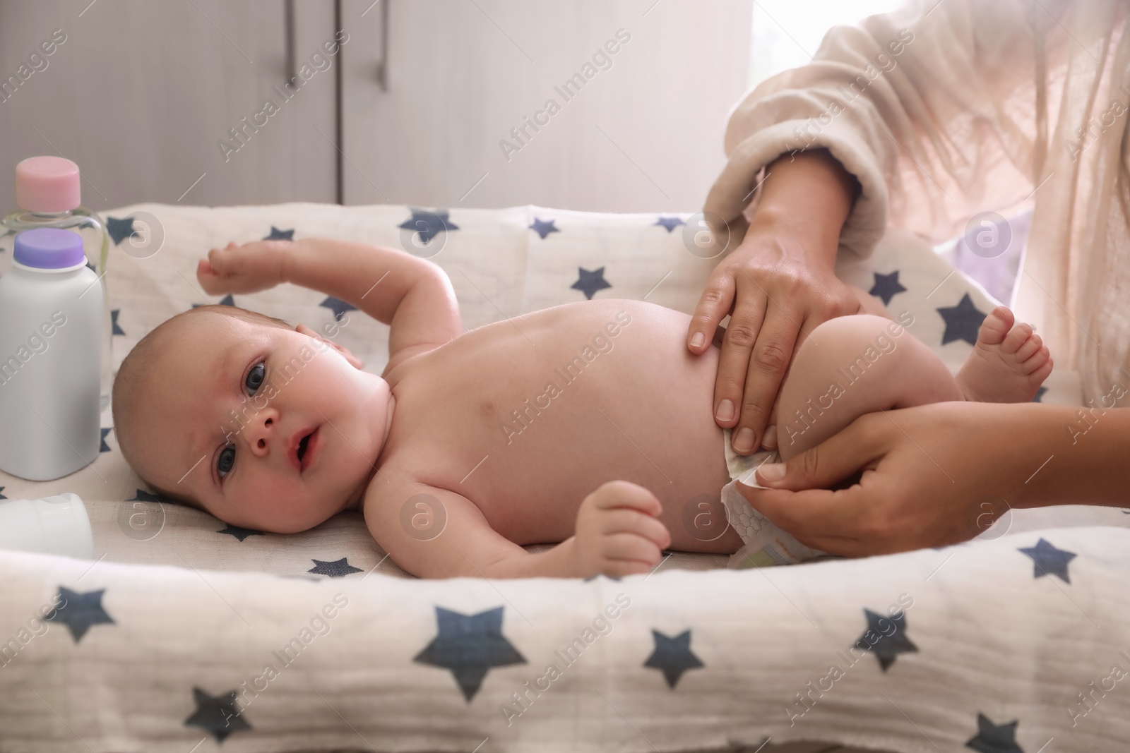 Photo of Mother changing baby's diaper on table indoors, closeup