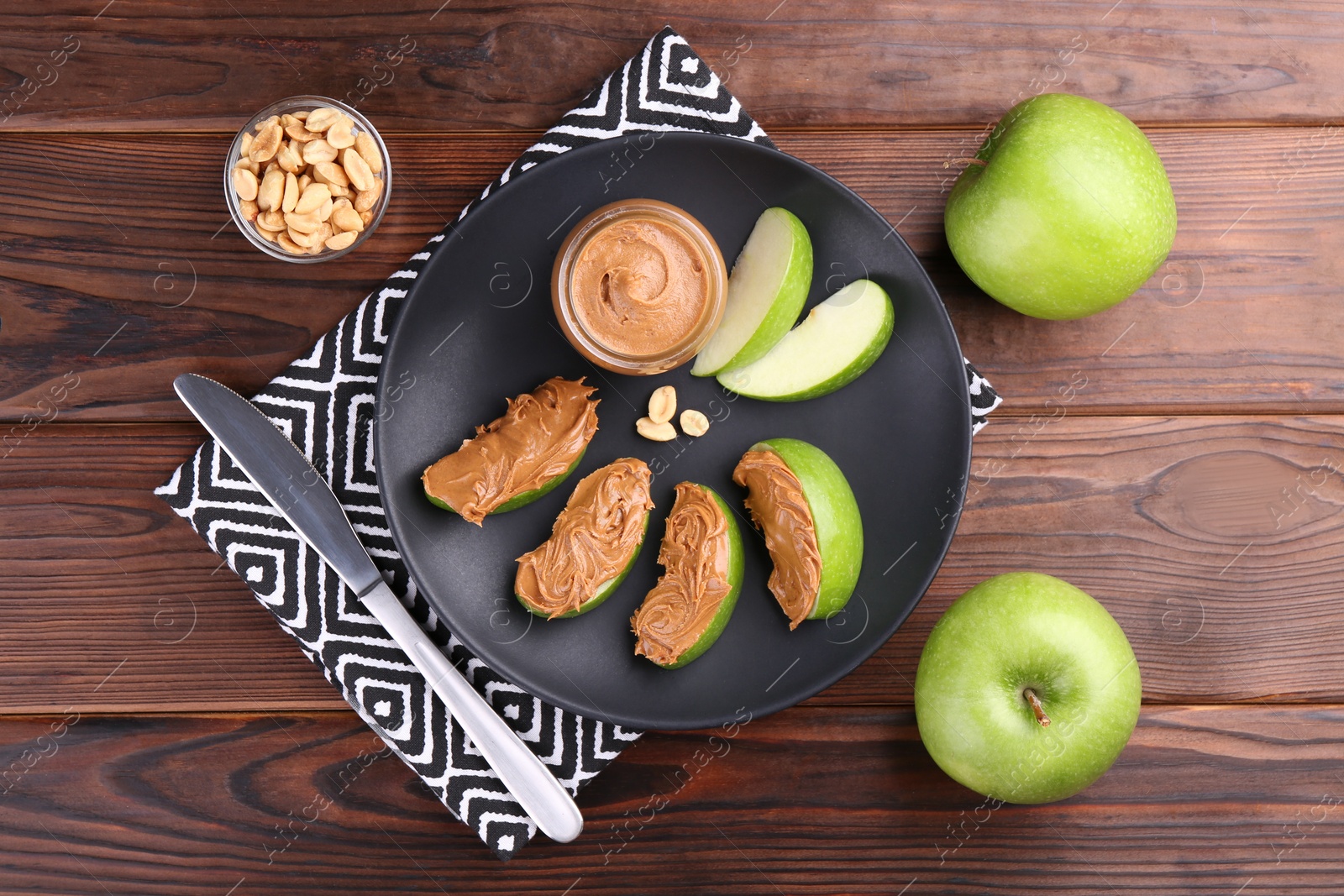 Photo of Slices of fresh green apple with peanut butter on wooden table, flat lay