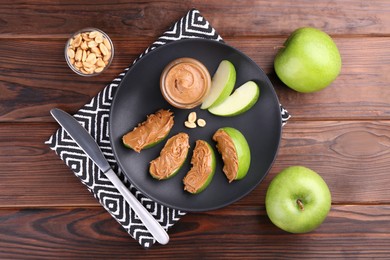 Photo of Slices of fresh green apple with peanut butter on wooden table, flat lay