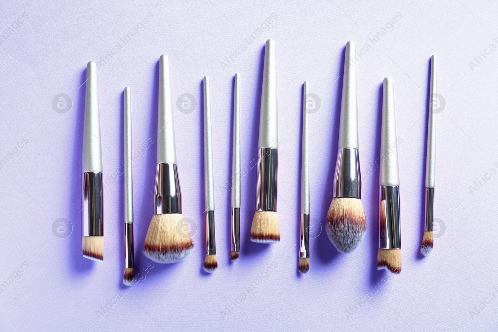 Photo of Many different makeup brushes on lilac background, flat lay