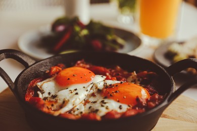 Tasty Shakshouka served in pan on table, closeup