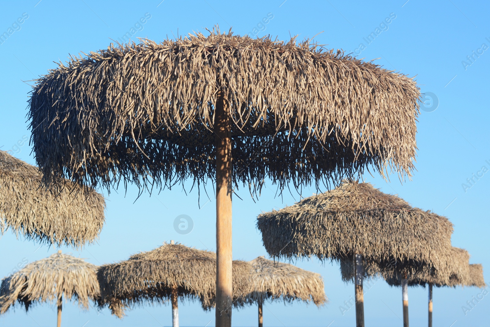 Photo of Beautiful straw beach umbrellas against blue sky