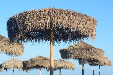 Beautiful straw beach umbrellas against blue sky