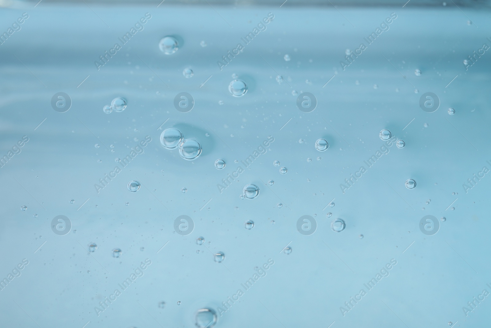 Photo of Pure transparent cosmetic gel on light blue background, closeup