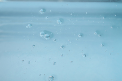 Photo of Pure transparent cosmetic gel on light blue background, closeup