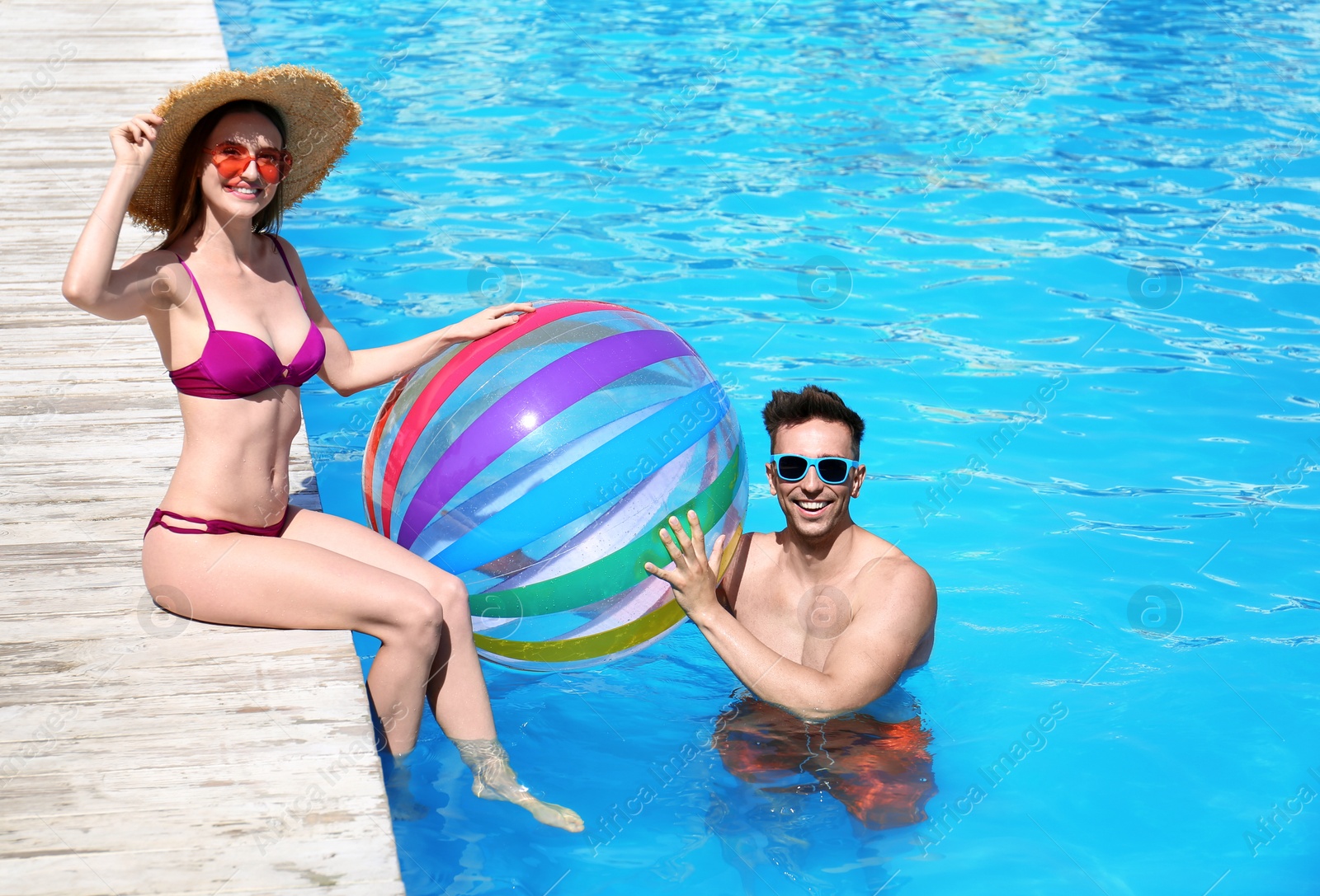 Photo of Happy young couple with inflatable ball at swimming pool