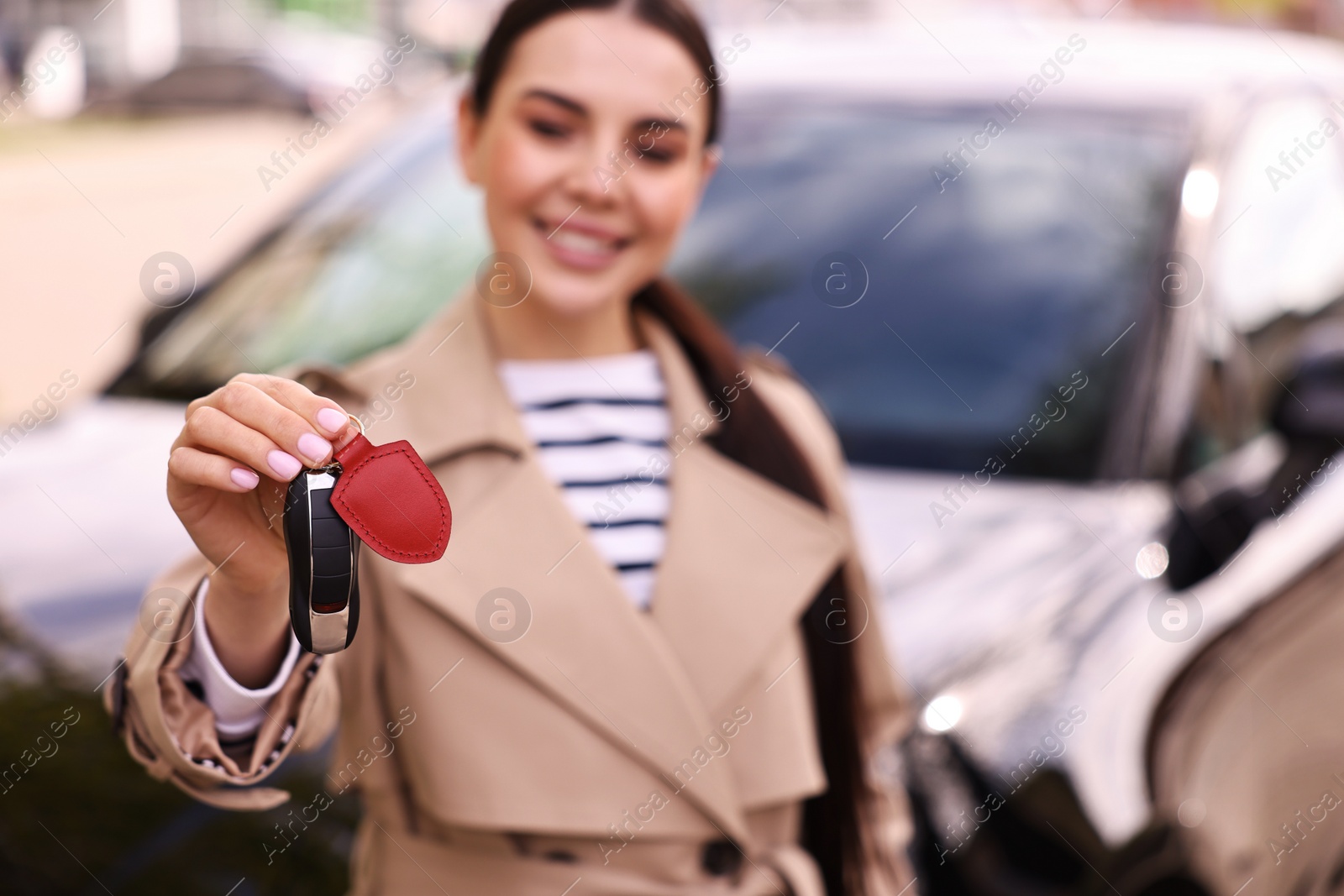 Photo of Woman holding car flip key near her vehicle outdoors, selective focus