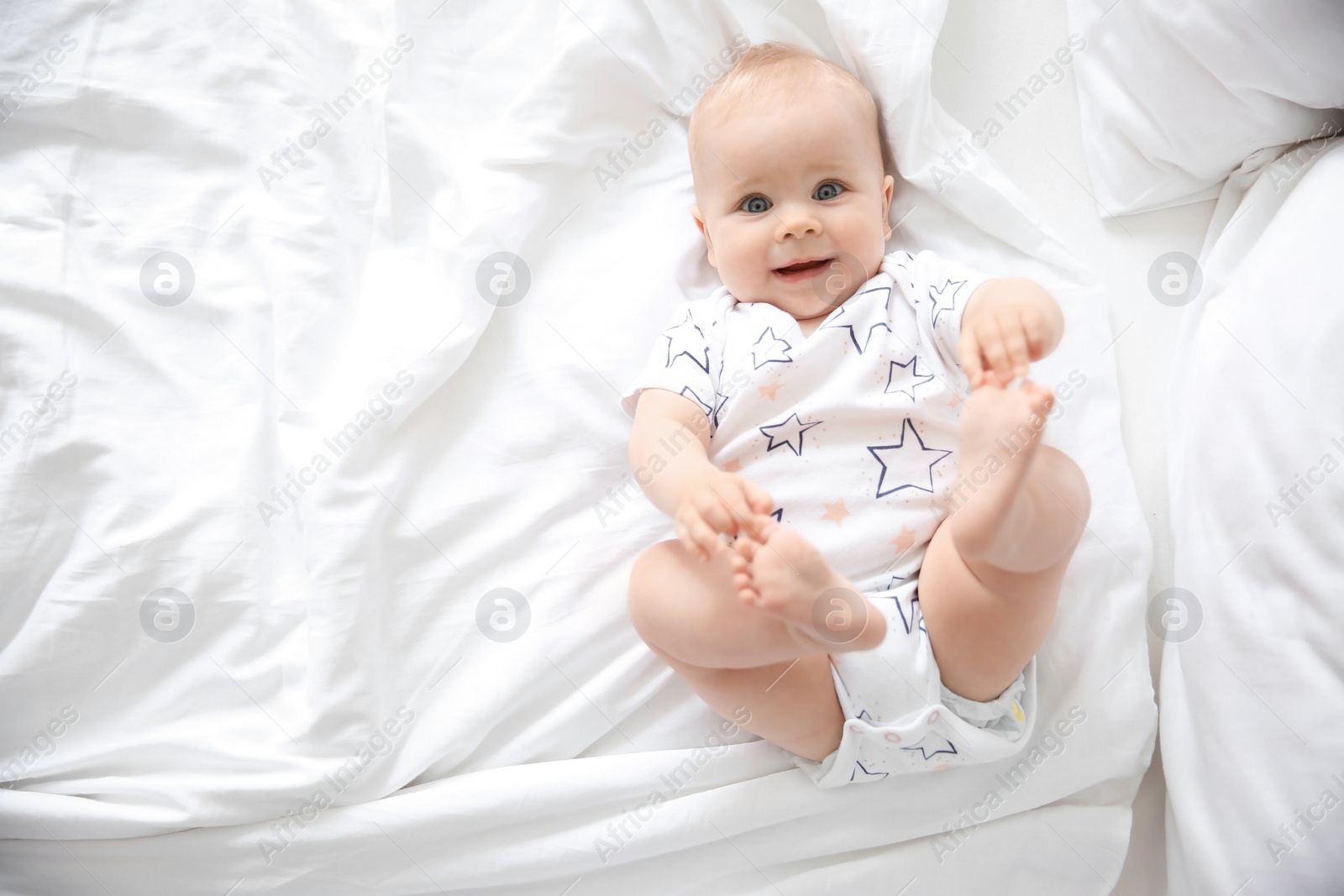 Photo of Cute little baby lying on bed, top view