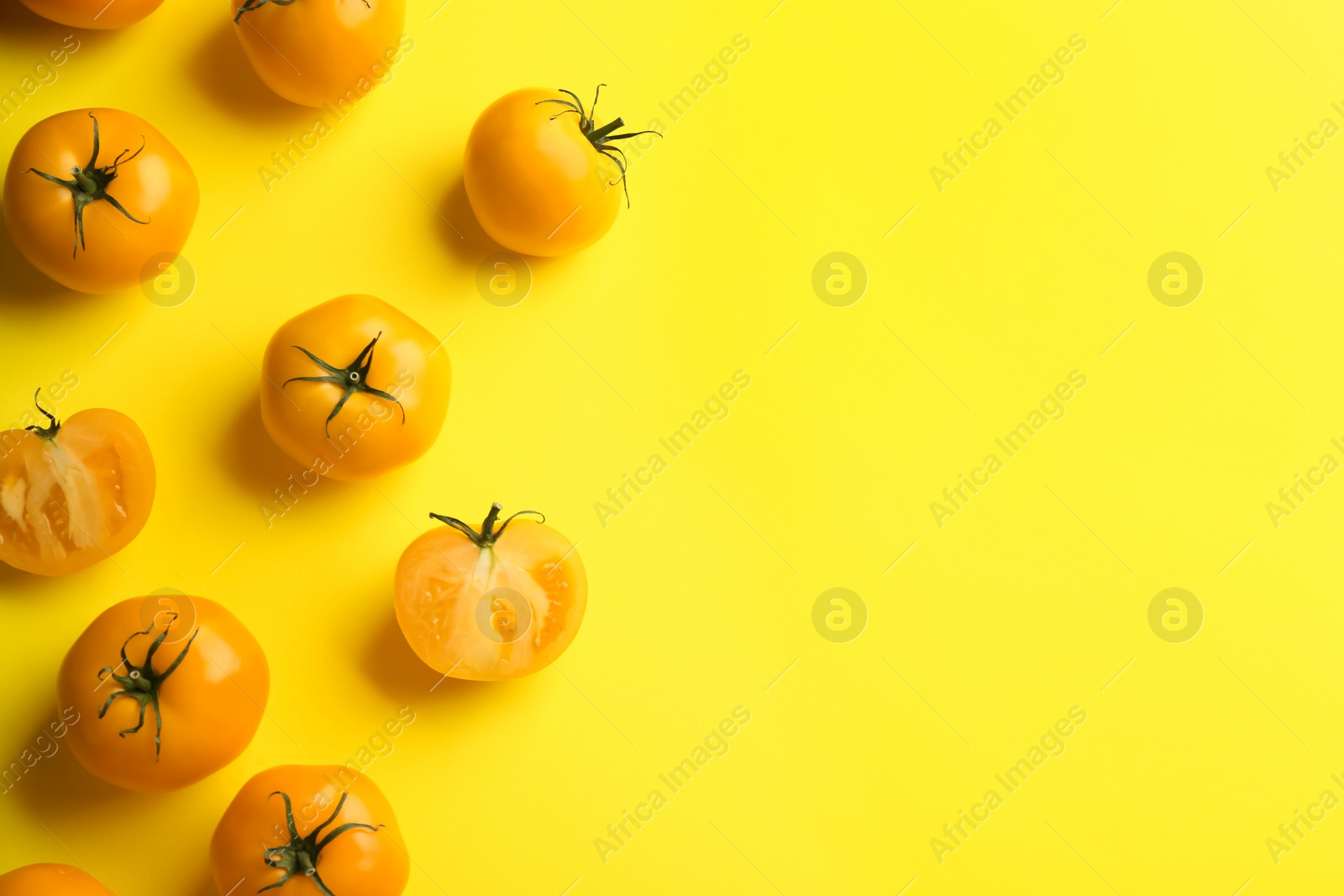 Photo of Yellow tomatoes on color background, flat lay. Space for text