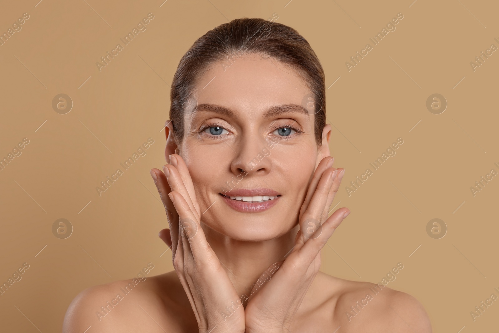 Photo of Woman massaging her face on beige background