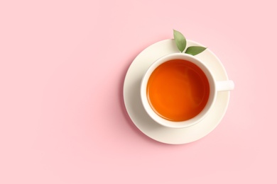 Photo of Cup of delicious tea with green leaves on color background, top view