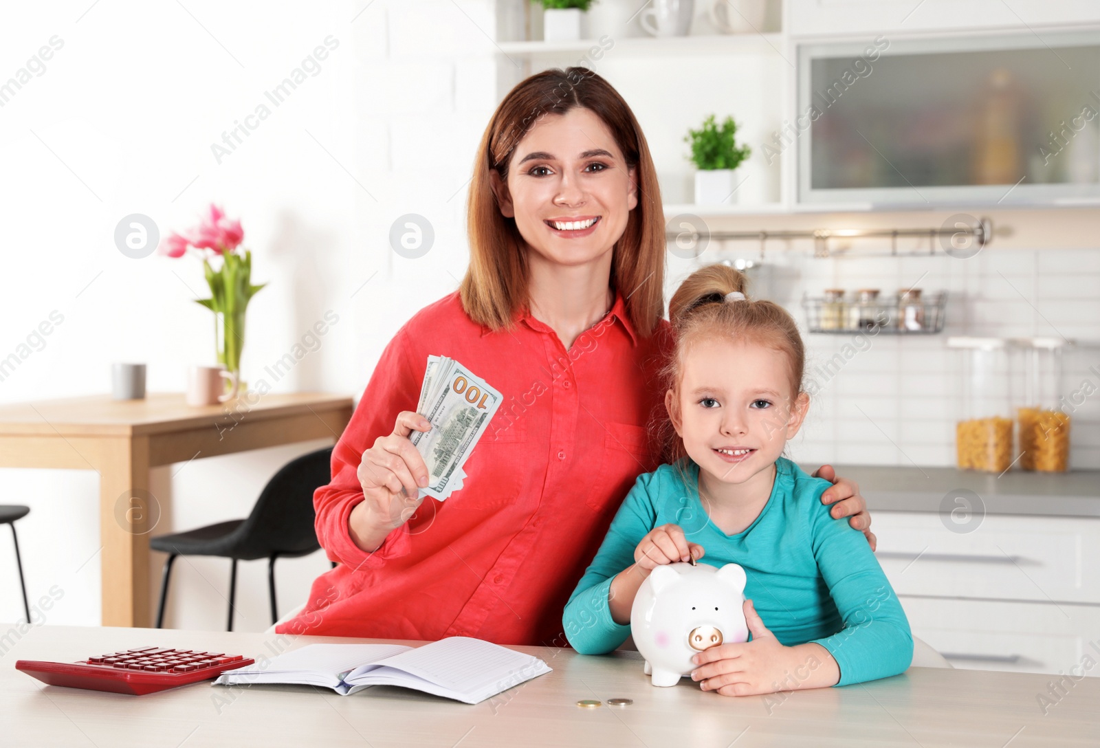 Photo of Mother and daughter with money at table in kitchen. Saving money