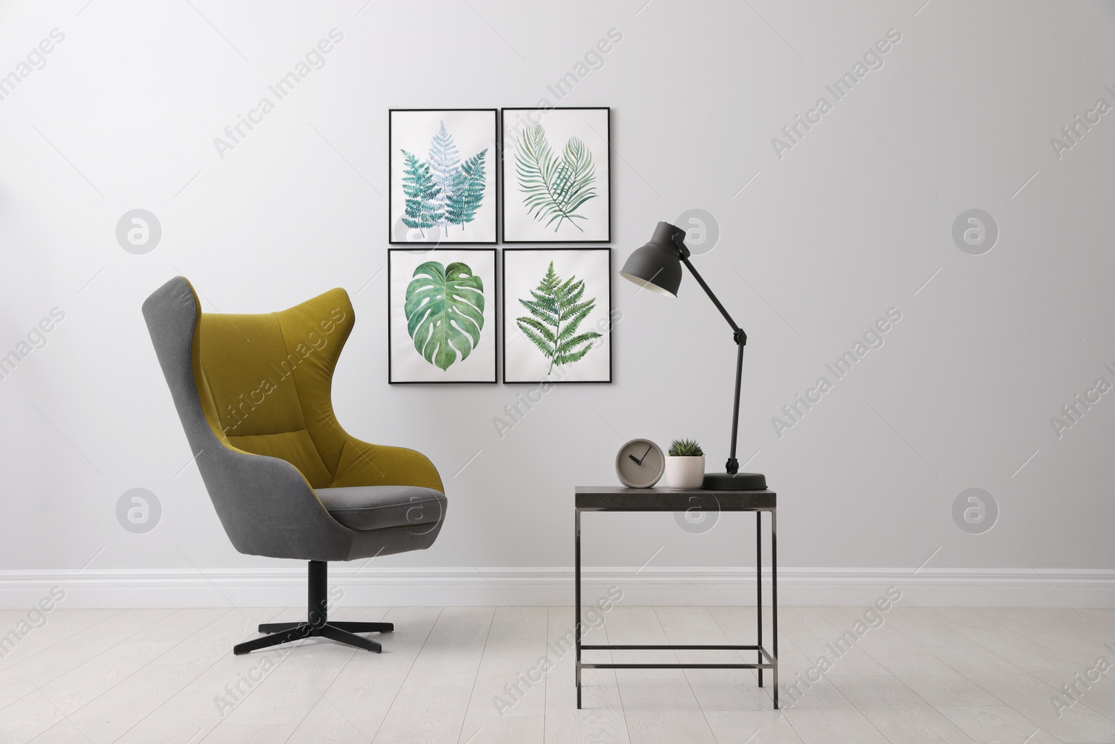 Photo of Stylish room interior with comfortable armchair and paintings of tropical leaves