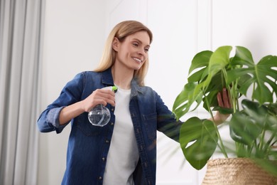 Photo of Woman spraying beautiful potted houseplant with water at home
