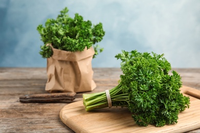 Photo of Cutting board with fresh green parsley on kitchen table