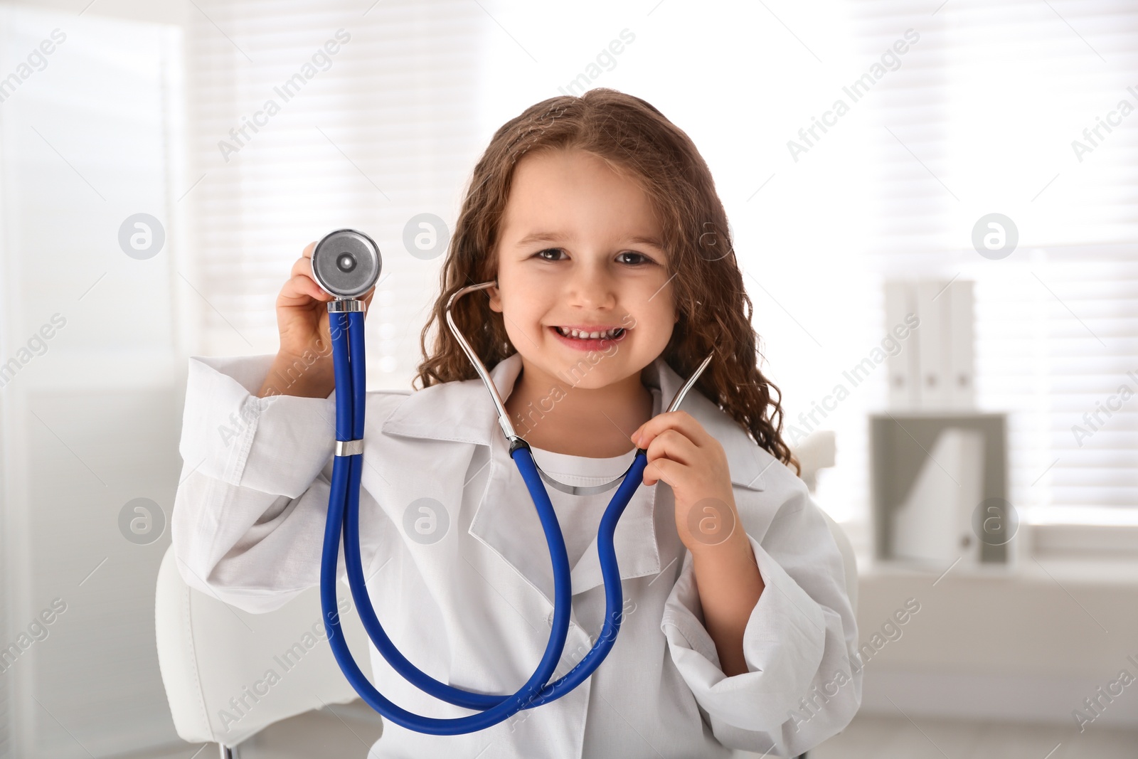 Photo of Cute little girl playing doctor in clinic