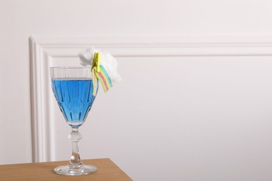 Photo of Bright cocktail in glass decorated with cotton candy and sour rainbow belt on wooden table, space for text