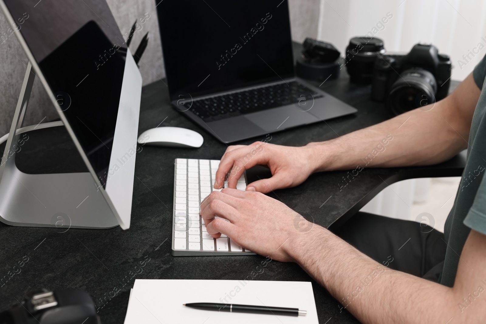 Photo of Photographer working on computer at dark table with camera, closeup