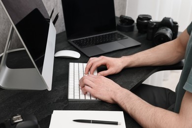 Photographer working on computer at dark table with camera, closeup