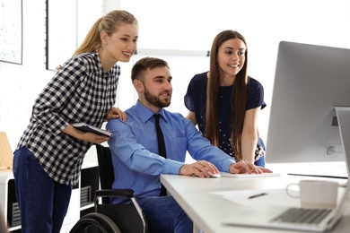 Man in wheelchair with his colleagues at workplace