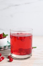 Tasty cranberry juice in glass and fresh berries on white wooden table