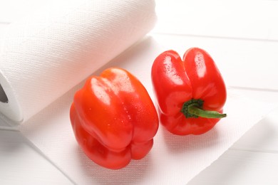 Photo of Rollpaper towels with wet bell peppers on white wooden table, closeup