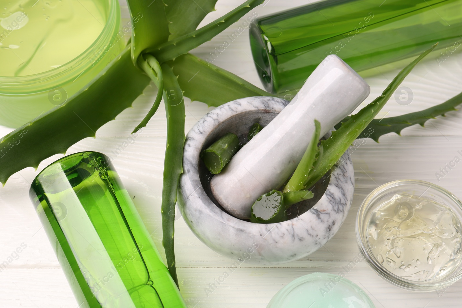 Photo of Homemade aloe gel and fresh ingredients on white wooden table, above view