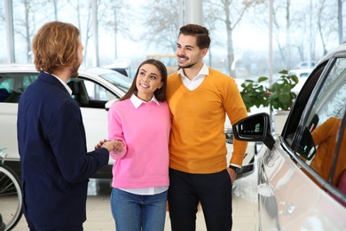 Car salesman working with couple in dealership