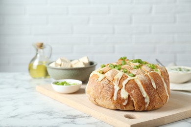 Photo of Freshly baked bread with tofu cheese and green onion on white marble table. Space for text