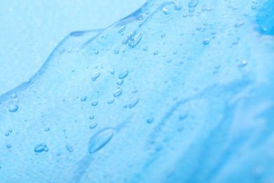 Photo of Pure transparent cosmetic gel on blue background, closeup