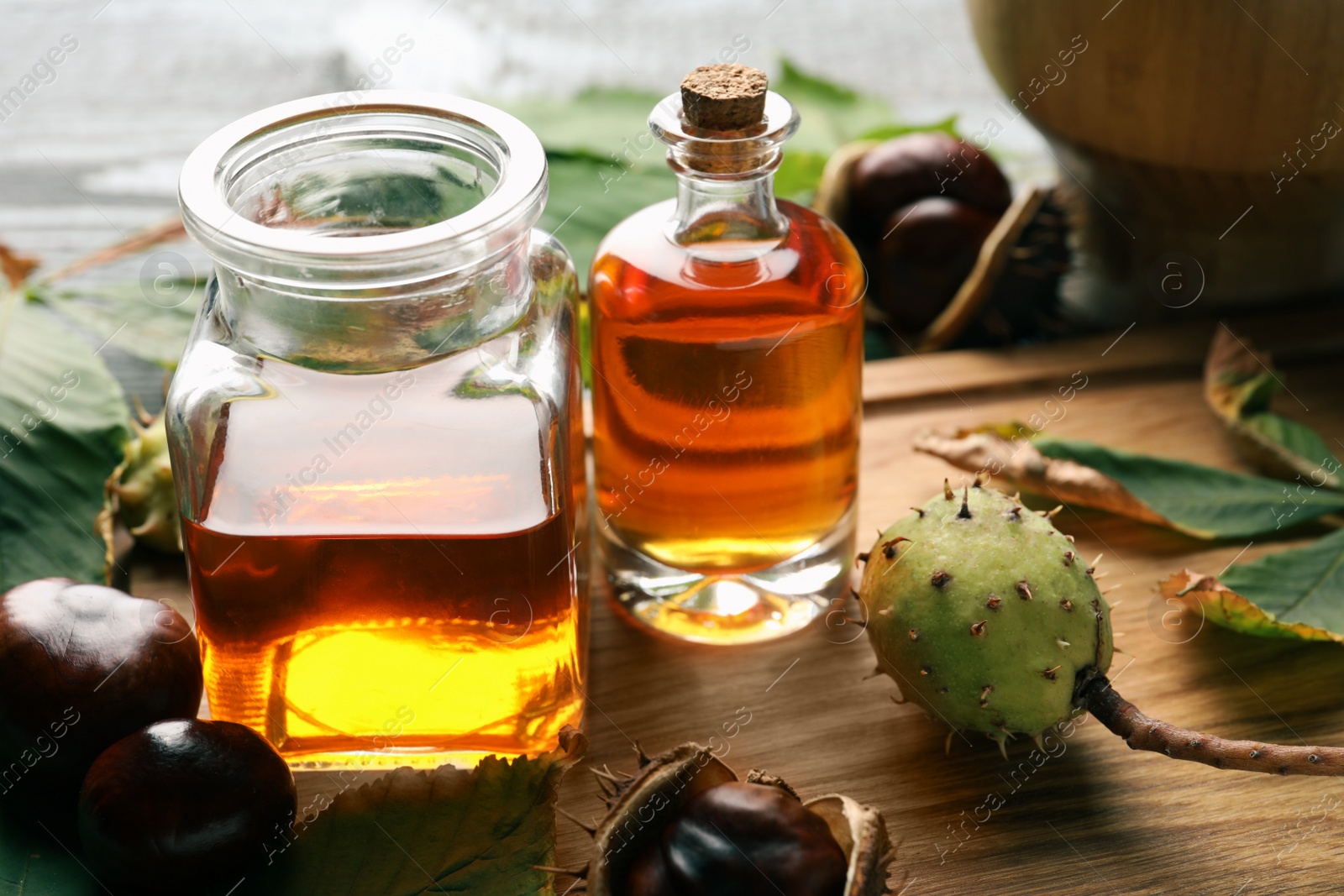 Photo of Horse chestnuts, leaves and bottles of tincture on wooden table, closeup