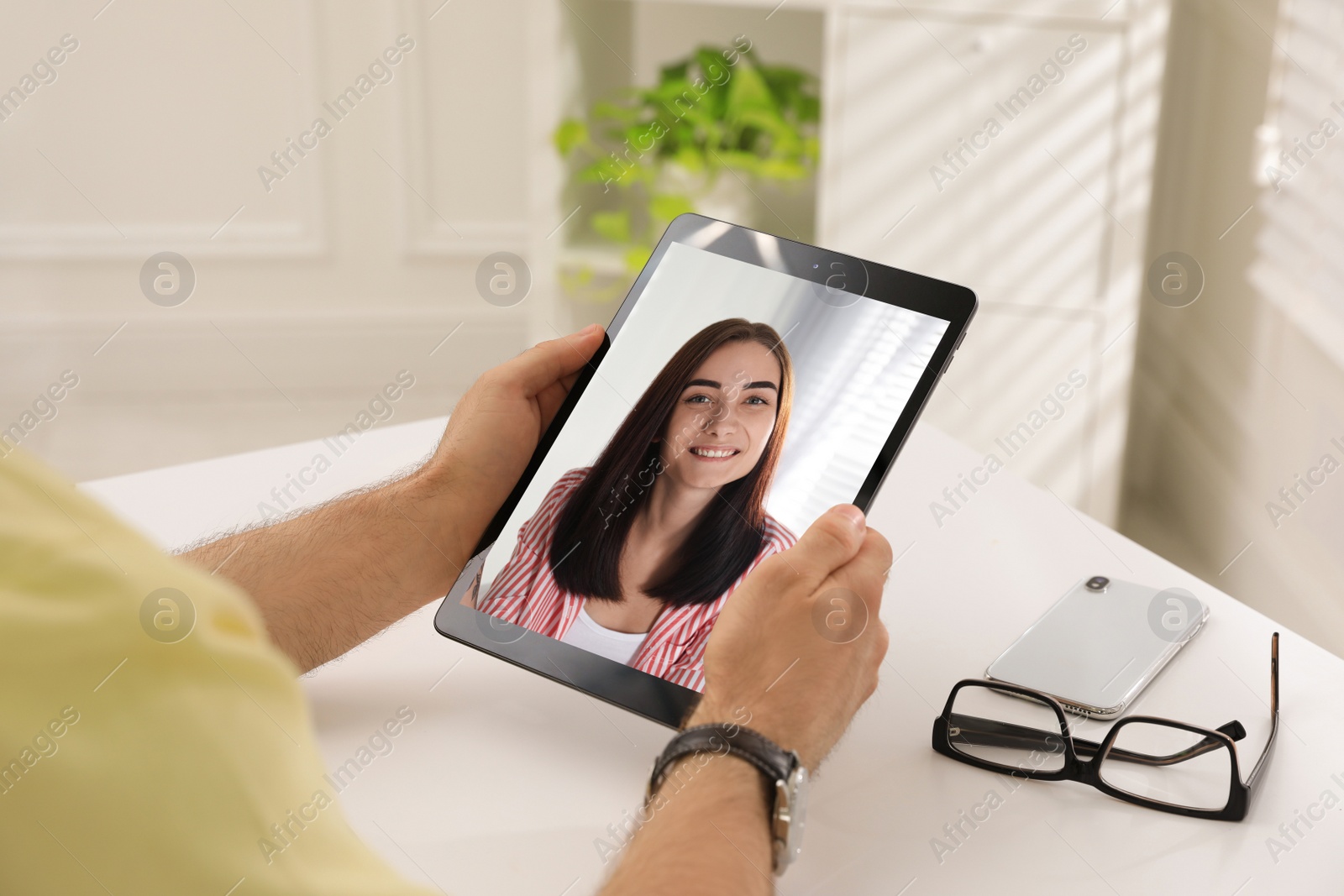 Image of Man talking with beautiful woman using video chat on tablet at white table, closeup. Online dating