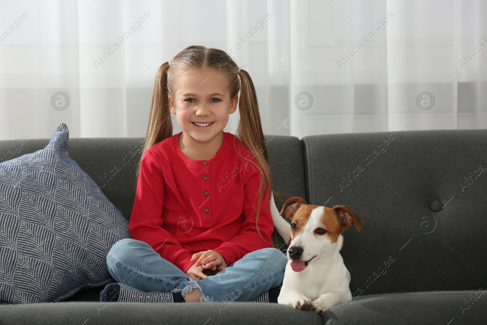 Photo of Cute girl with her dog on sofa at home. Adorable pet