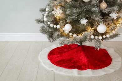 Decorated Christmas tree with red skirt indoors