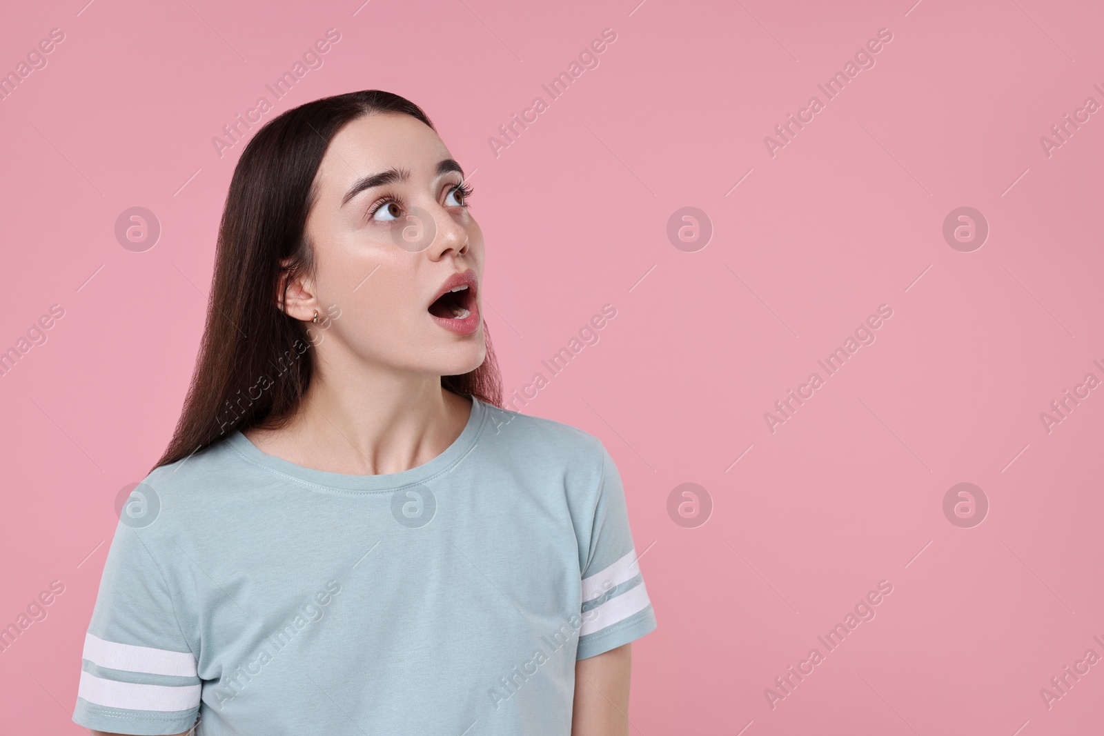 Photo of Portrait of surprised woman on pink background. Space for text