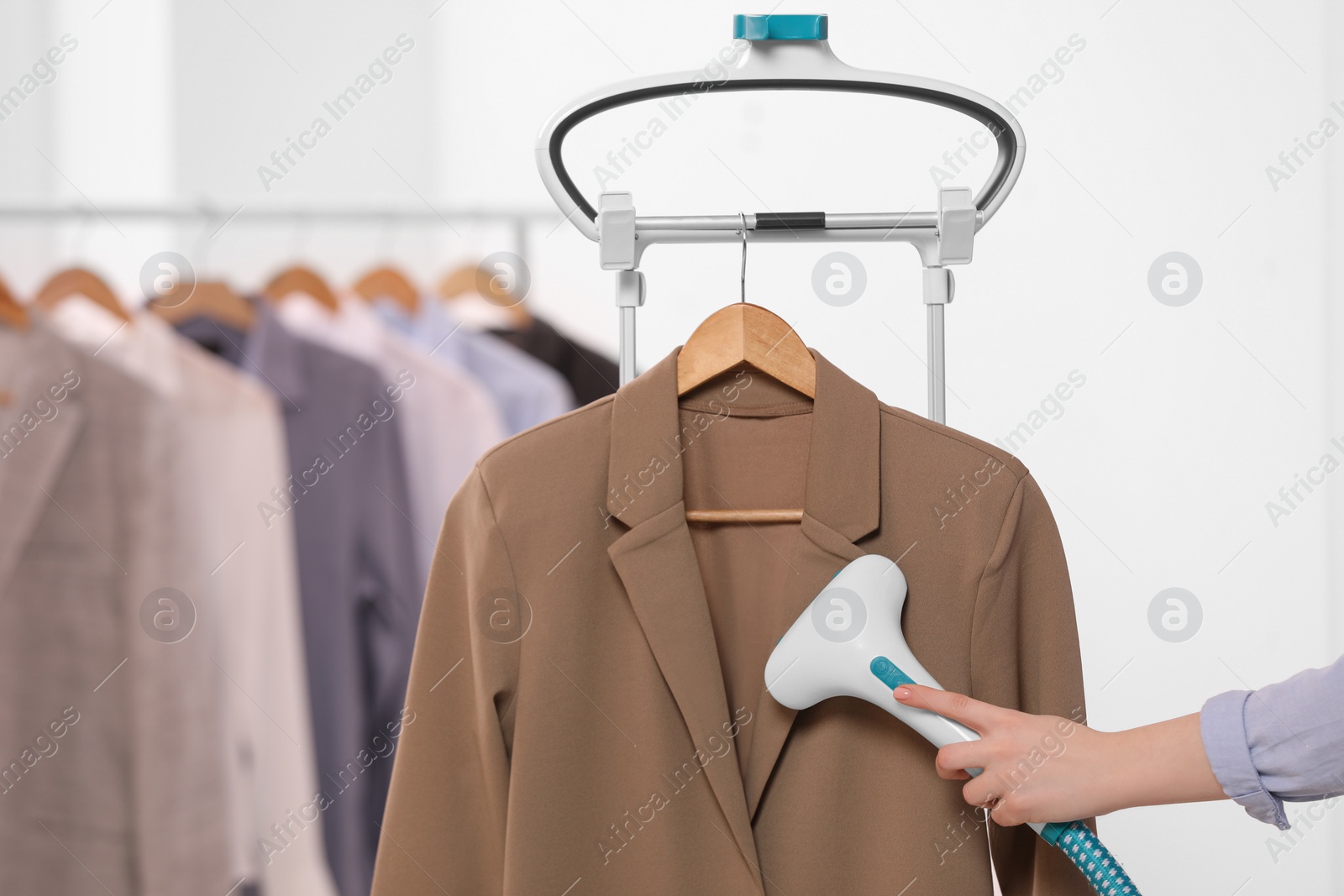 Photo of Woman steaming jacket on hanger in room, closeup