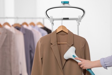 Photo of Woman steaming jacket on hanger in room, closeup