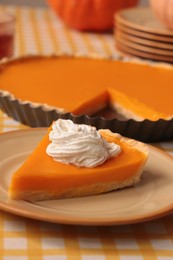 Photo of Piece of fresh homemade pumpkin pie with whipped cream on table