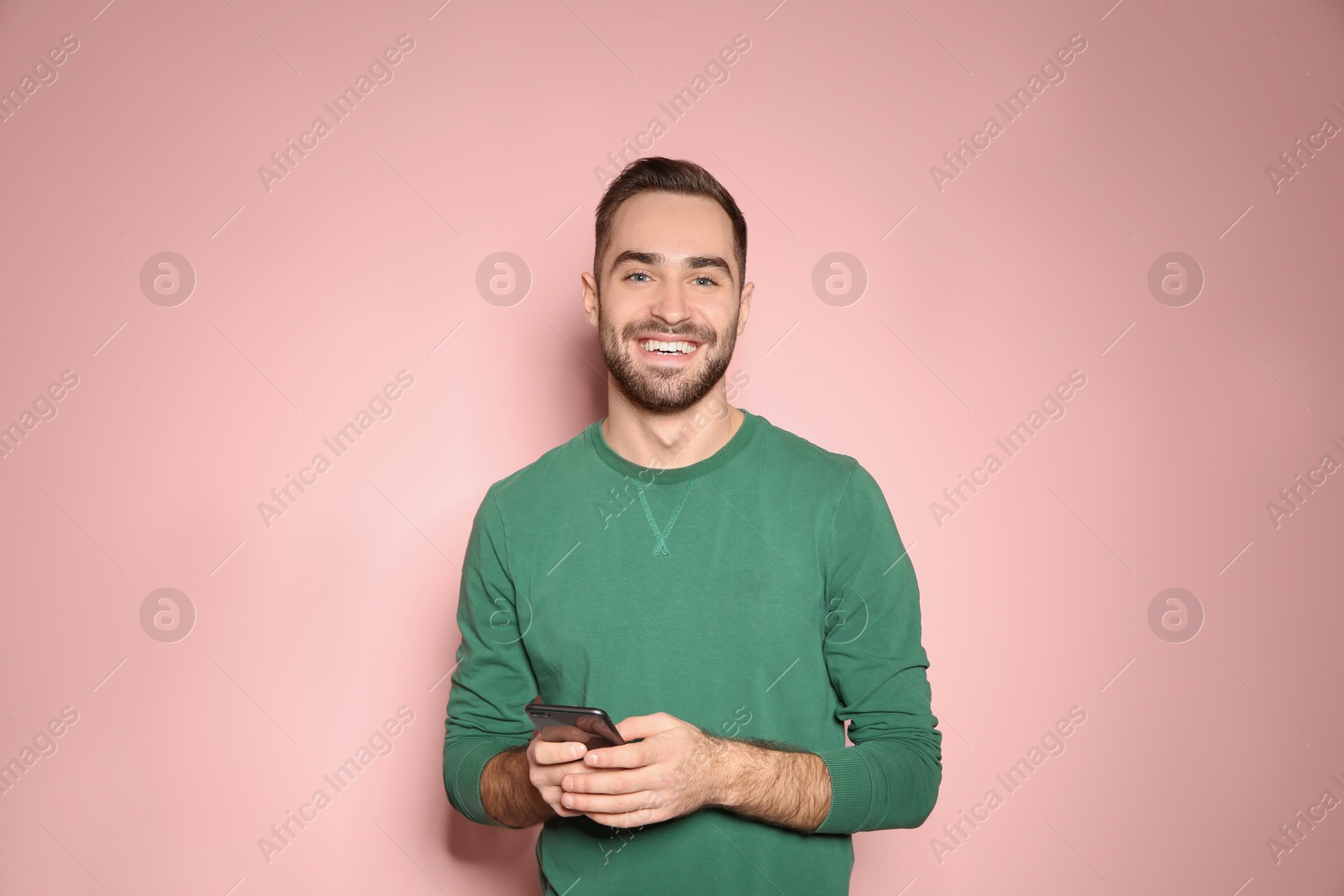 Photo of Handsome young man with mobile phone on color background