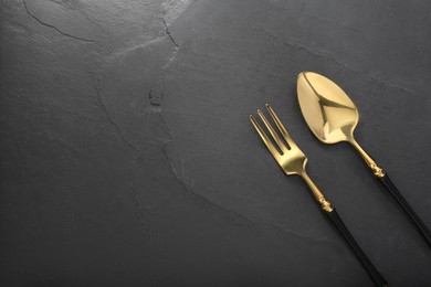 Photo of Shiny fork and spoon on black table, flat lay. Space for text